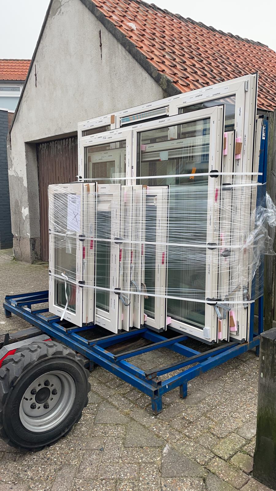 Stapel nieuwe witte kunststof kozijnen, ingepakt op een aanhanger