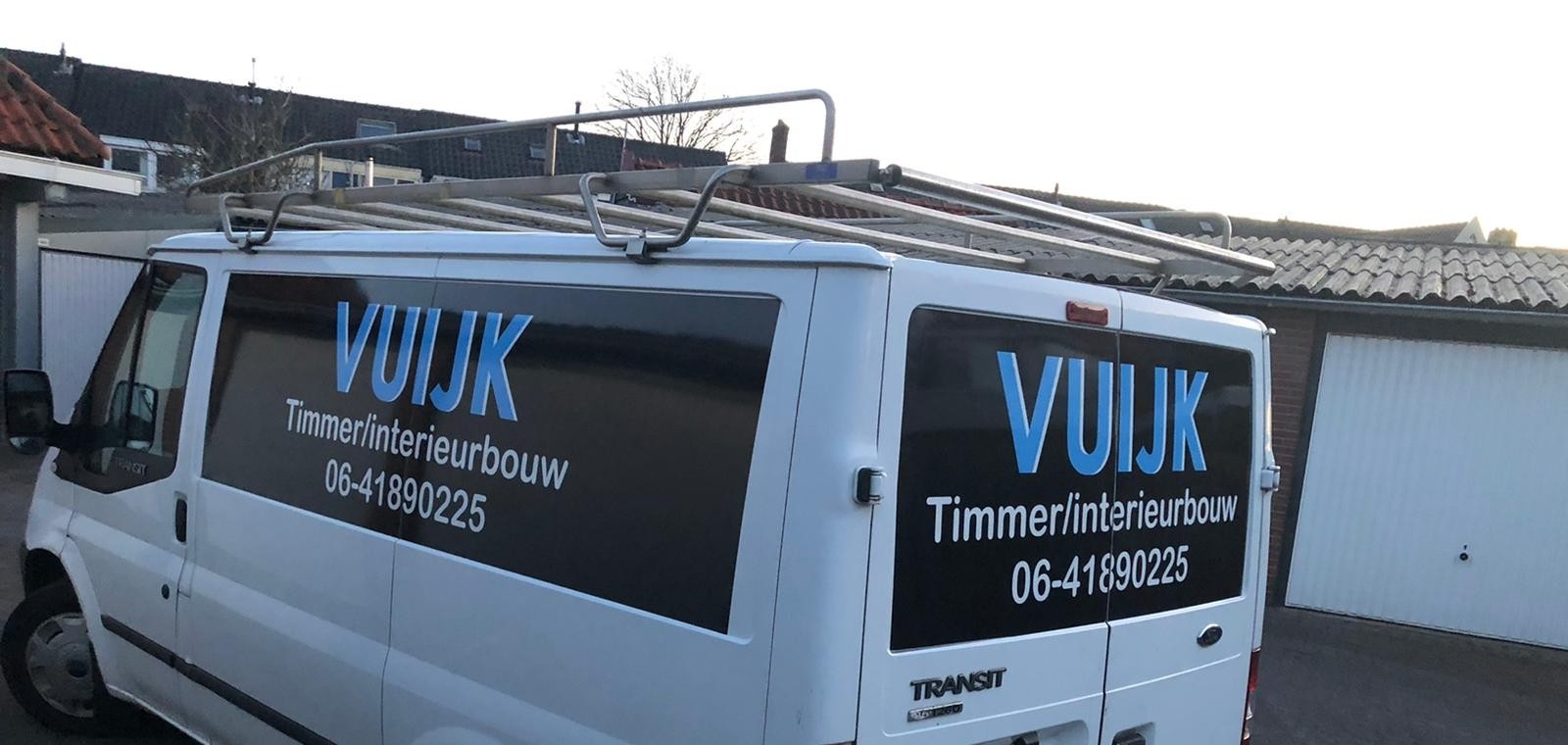 Witte bedrijfsbus met op de ramen VUIJK Timmer/interieurbouw en het telefoonnummer