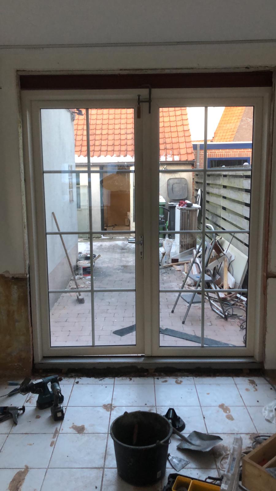 Nieuwe witte openslaande tuindeuren met roedes, tijdens de werkzaamheden